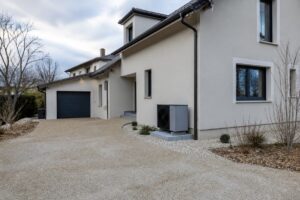 Unité extérieure d'une pompe à chaleur installée discrètement le long de la façade d'une maison individuelle rénovée en hiver.
